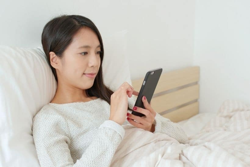 woman in bed using phone