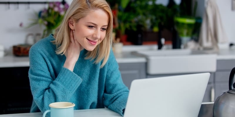 woman in blue blouse smiling in front of laptop